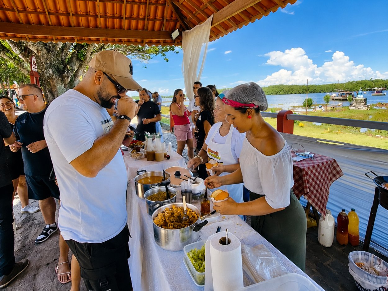 Grupo provando casquinha de siri em quiosque à beira do rio, em Canavieiras
